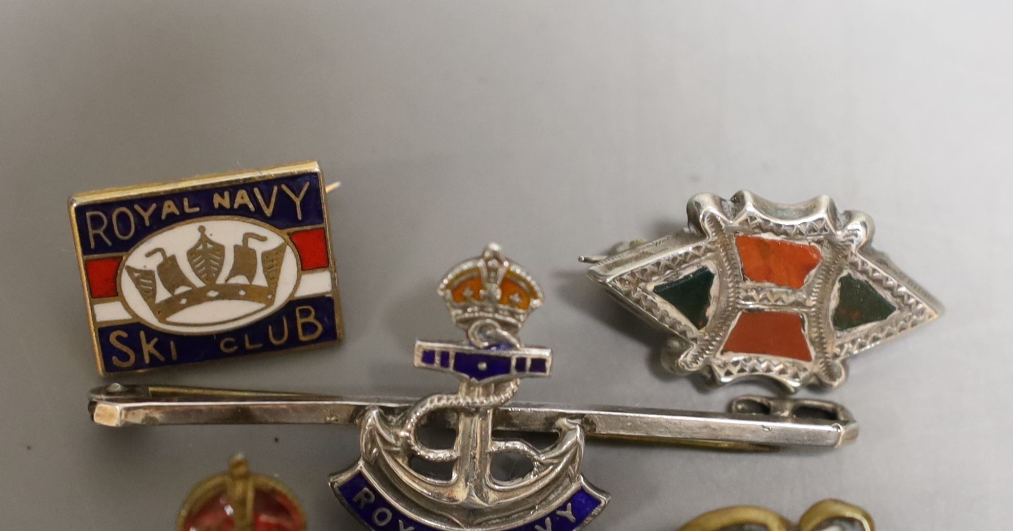 Four military badges: A Royal Navy badge and ski club badge, South Africa badge and another.